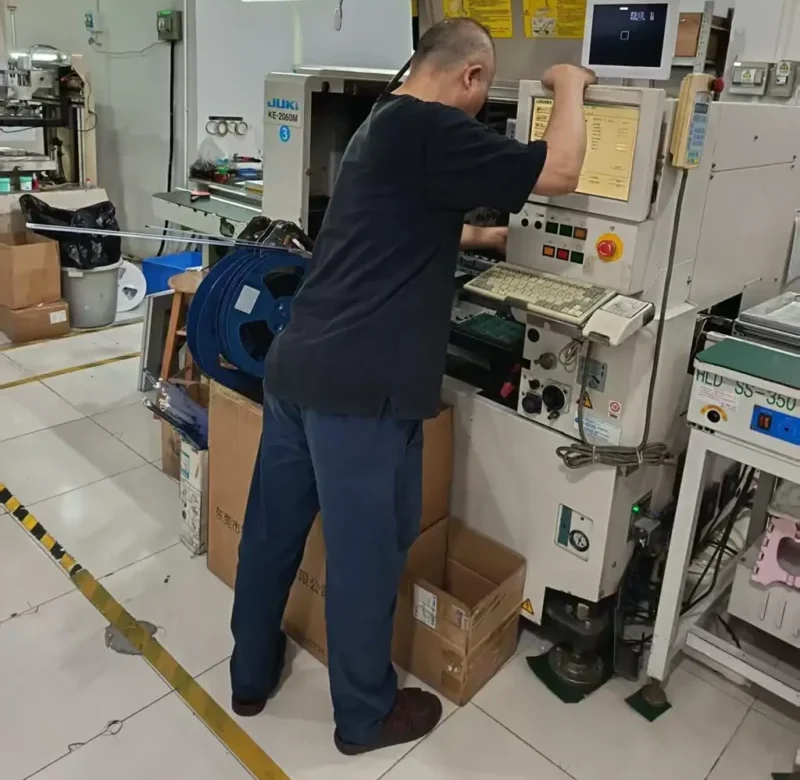 A hardware technician configuring precision manufacturing equipment inside the family-powered electronics factory of Shenzhen Kaiming Technology Co., Ltd. for WillPower automotive-grade smart switch PCB assembly.
